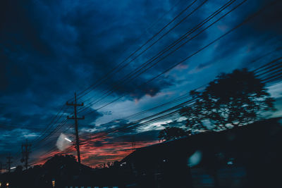 Low angle view of silhouette electricity pylon against sky