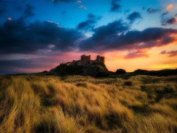 Castle on field against sky during sunset