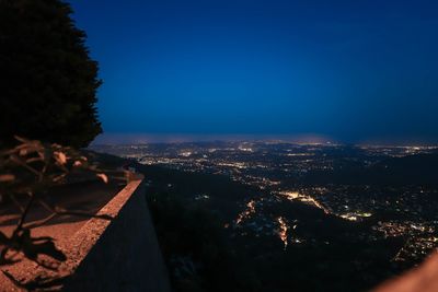 Aerial view of cityscape against clear blue sky at night