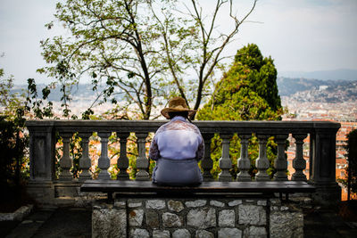 Full length of man sitting on railing against trees