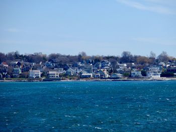 Sea by buildings against blue sky