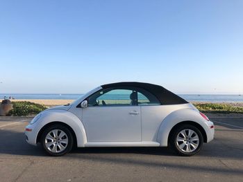 Vintage car on road by sea against clear blue sky