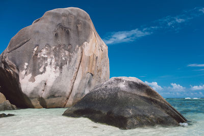 Rock formation in sea against blue sky