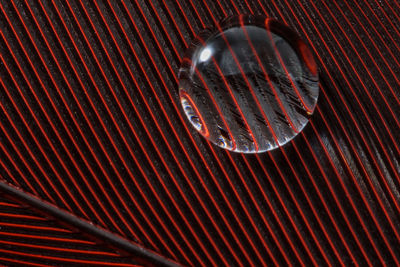 Close-up of water drop on red pattern