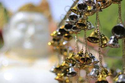 Close-up of small bells hanging against buddha statue