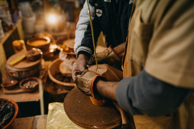 Midsection of potter working at workshop
