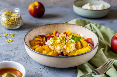 Healthy fruit salad with nectarine, ricotta cream with pistachios and honey, close up