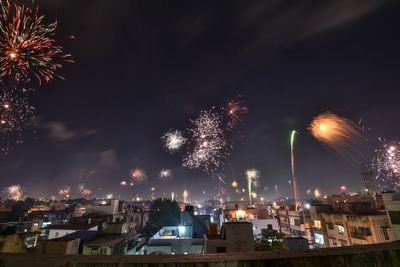 Firework display over illuminated buildings in city at night