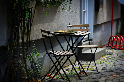 Empty chairs and tables against building