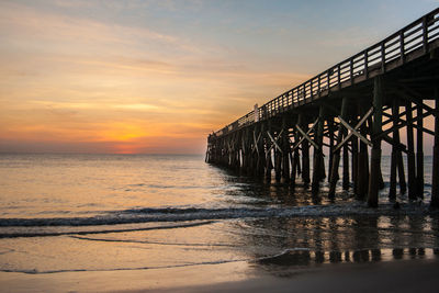 Pier over sea against sky during sunset