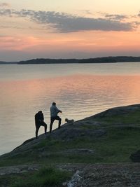 Men standing on beach against sky during sunset