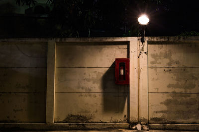 Illuminated street light by building at night