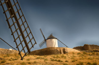 Low angle view of traditional windmill on field against sky