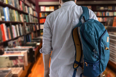 Rear view of man with backpack walking in library