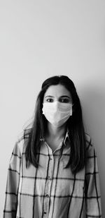 Portrait of young woman standing against white background