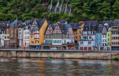 Houses by river against buildings in city