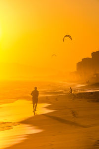 Silhouette man standing on beach against sky during sunset