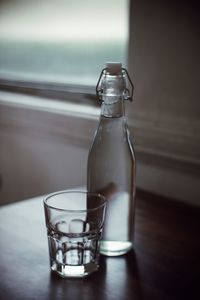 Water in bottle by glass on table