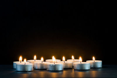 Close-up of candles burning on table against black background