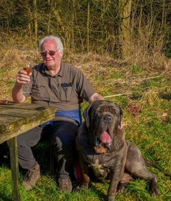 Mature man enjoying wine while sitting with dog in yard