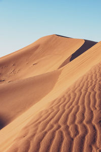 Sand dunes in desert against clear sky