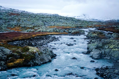 River flowing through rocks against sky