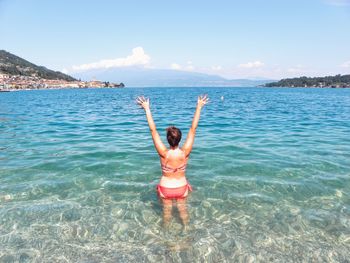 Young woman standing in sea against sky