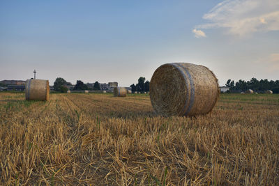 Hay bales on field against sky