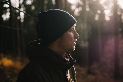 Side view of young man standing in forest