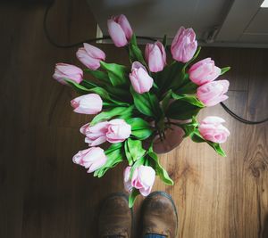 Low section of man by pink flowers on hardwood floor