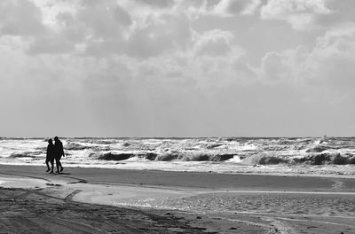 People walking on beach against sky