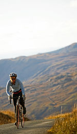 Female cyclist approaching top of a hill at the british lake district