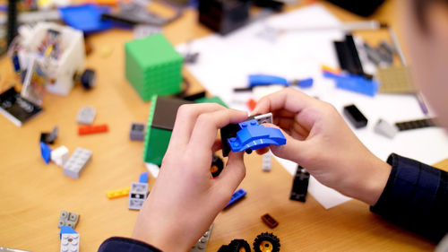 Close-up, children's hands hold a multicolored small robot, machine, assembled from a designer. 