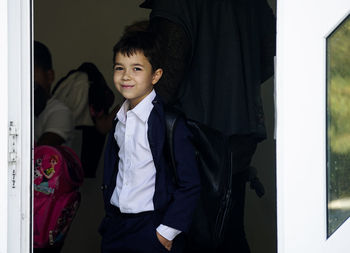 Portrait of smiling boy standing against door