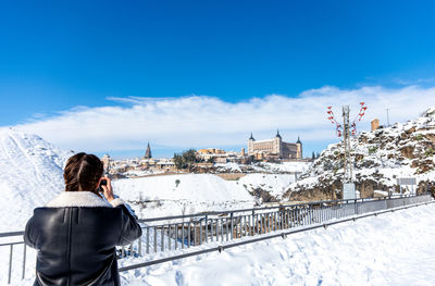 Rear view of woman standing on snowcapped mountain against sky