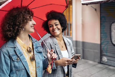 Smiling young woman using mobile phone in city