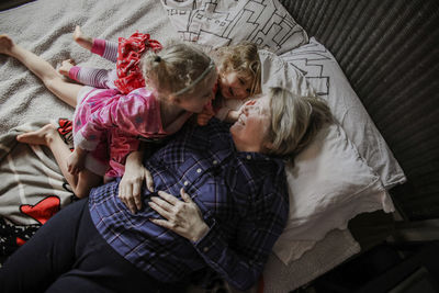 Overhead view of happy granddaughters with grandmother on bed