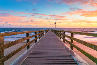 Pier over sea against sky during sunset