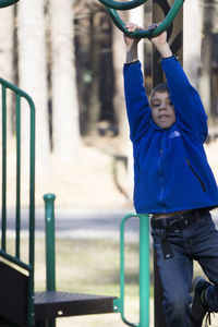 Portrait of boy hanging on metal structure at park