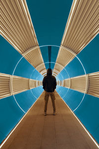 Rear view of man standing on illuminated ceiling