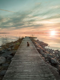 Pier amidst sea against sky during sunset