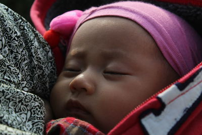 Close-up of cute baby girl sleeping in carrier
