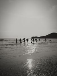 Silhouette people on beach against sky