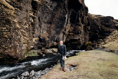 Rear view of man walking on rocks by mountain