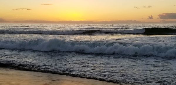 Waves rushing towards shore during sunset