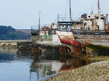 Abandoned boats moored on shore against sky