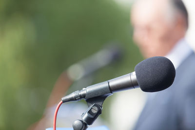 Close-up of microphone with businessman standing in background