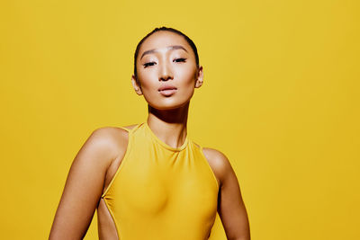 Portrait of young woman against yellow background