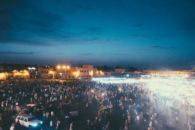 Crowd at illuminated city against sky at night