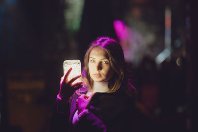 Portrait of beautiful woman holding glowing jar at night
